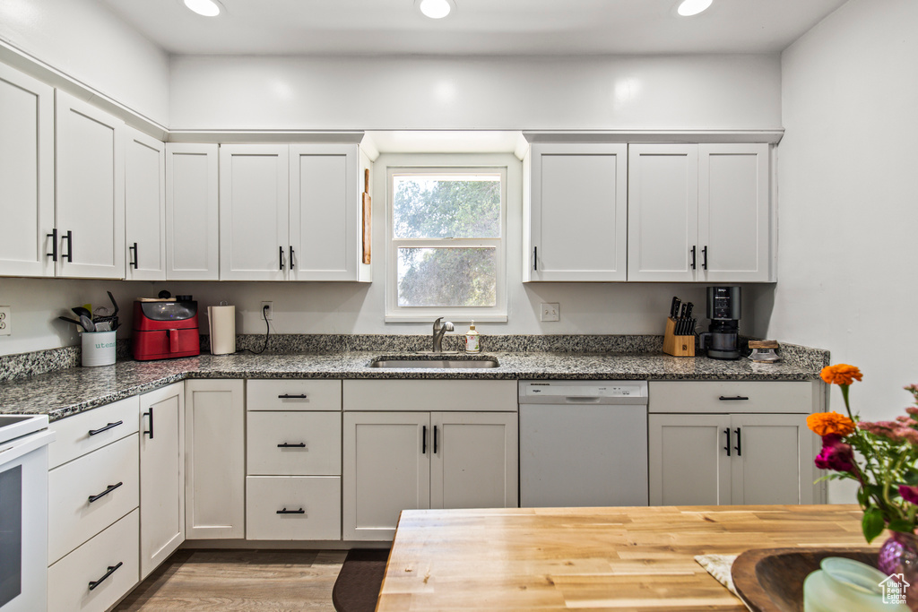 Kitchen featuring white appliances, white cabinetry, sink, and light hardwood / wood-style flooring