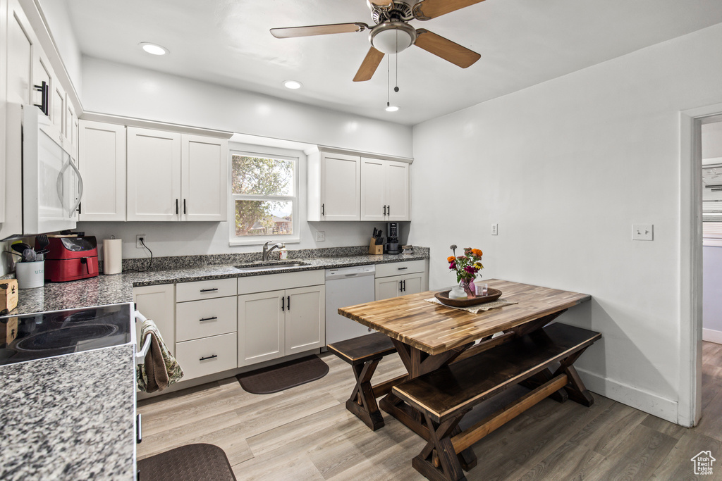 Kitchen featuring light hardwood / wood-style floors, white cabinetry, white appliances, light stone countertops, and ceiling fan