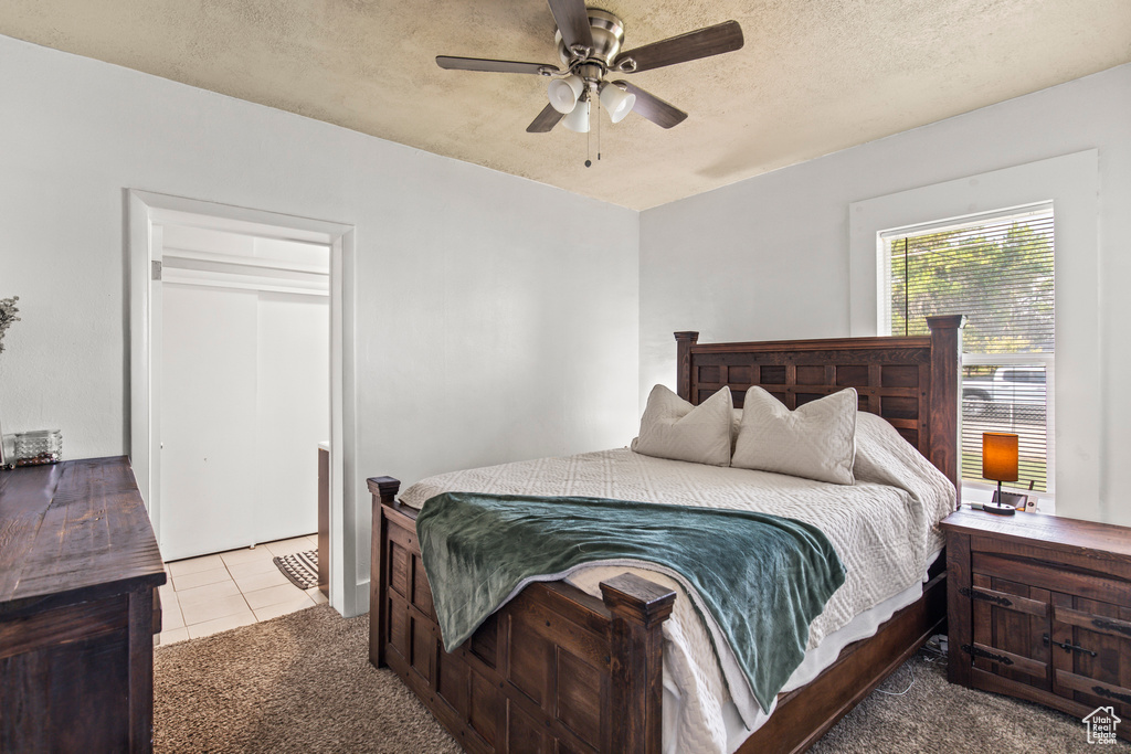 Carpeted bedroom featuring a closet, ceiling fan, and a textured ceiling