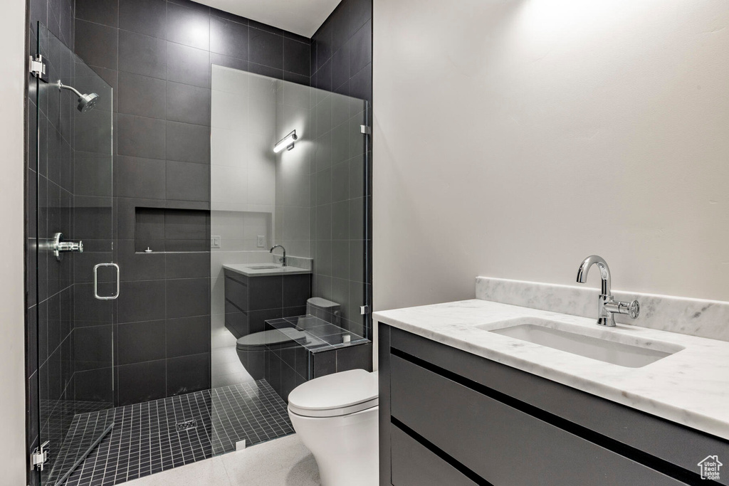 Bathroom featuring walk in shower, vanity, toilet, and tile patterned floors