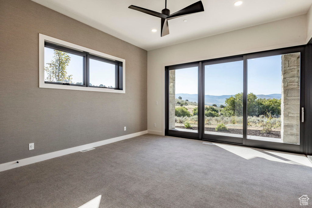 Carpeted spare room with ceiling fan, a mountain view, and a wealth of natural light