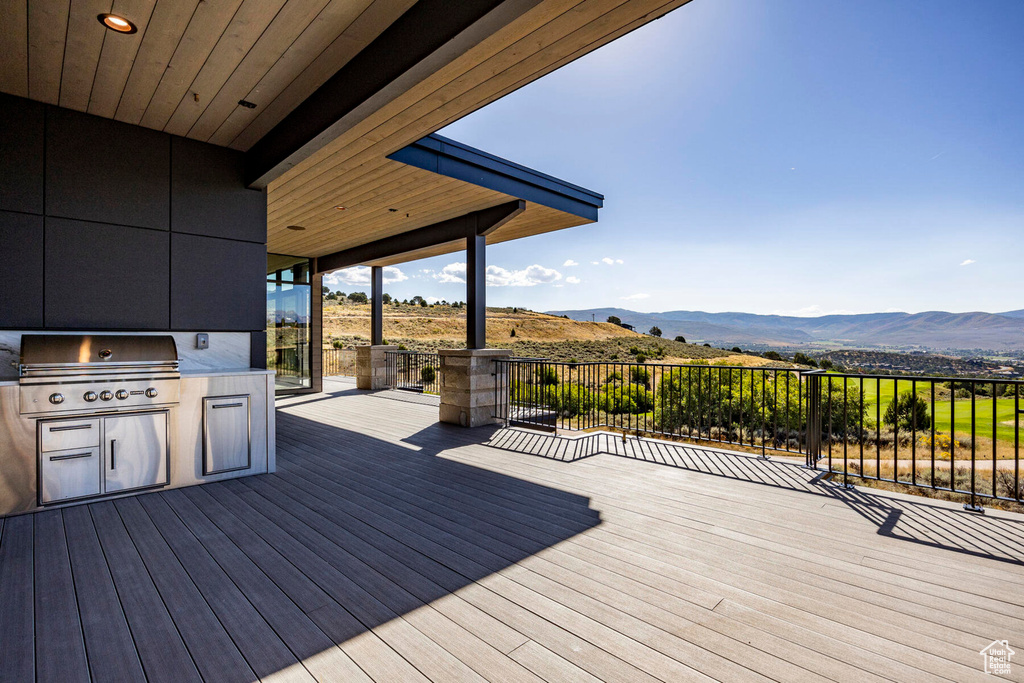 Wooden terrace featuring a grill, a mountain view, and exterior kitchen