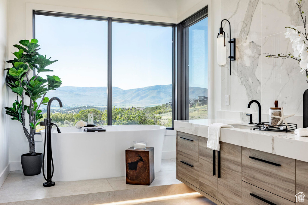 Bathroom featuring a mountain view, a bath, plenty of natural light, and vanity