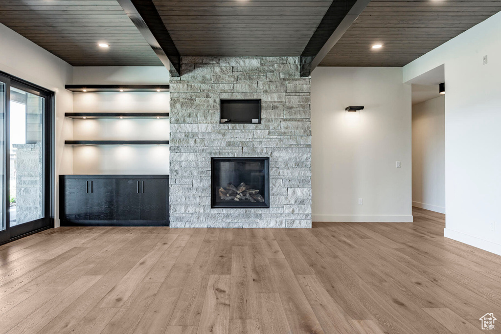 Unfurnished living room with light hardwood / wood-style flooring, wooden ceiling, and a fireplace