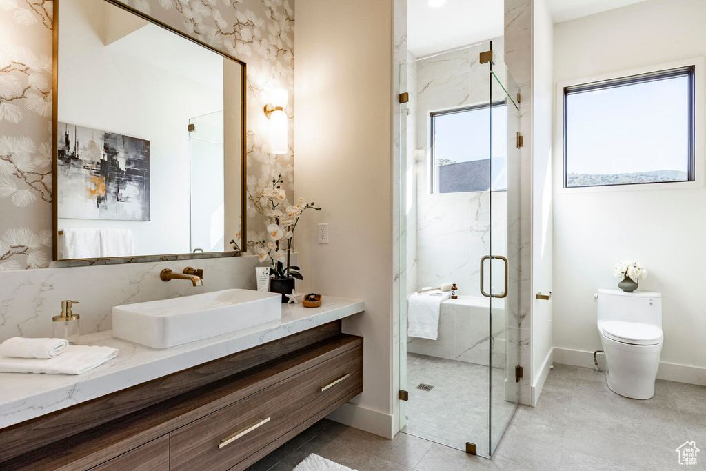 Bathroom with tile patterned flooring, a shower with door, vanity, and toilet