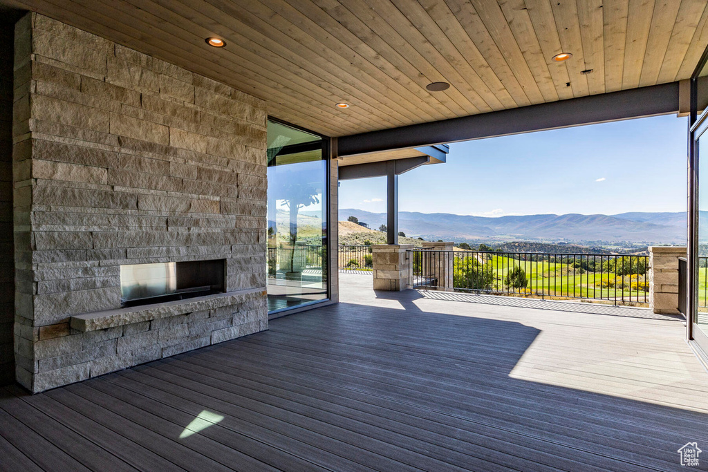 Wooden deck featuring a mountain view and an outdoor stone fireplace