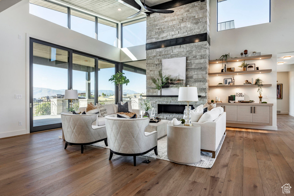 Living room with a healthy amount of sunlight, a stone fireplace, and hardwood / wood-style floors