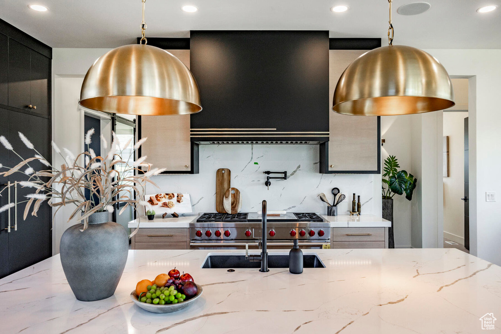 Kitchen with light stone countertops, hanging light fixtures, and decorative backsplash