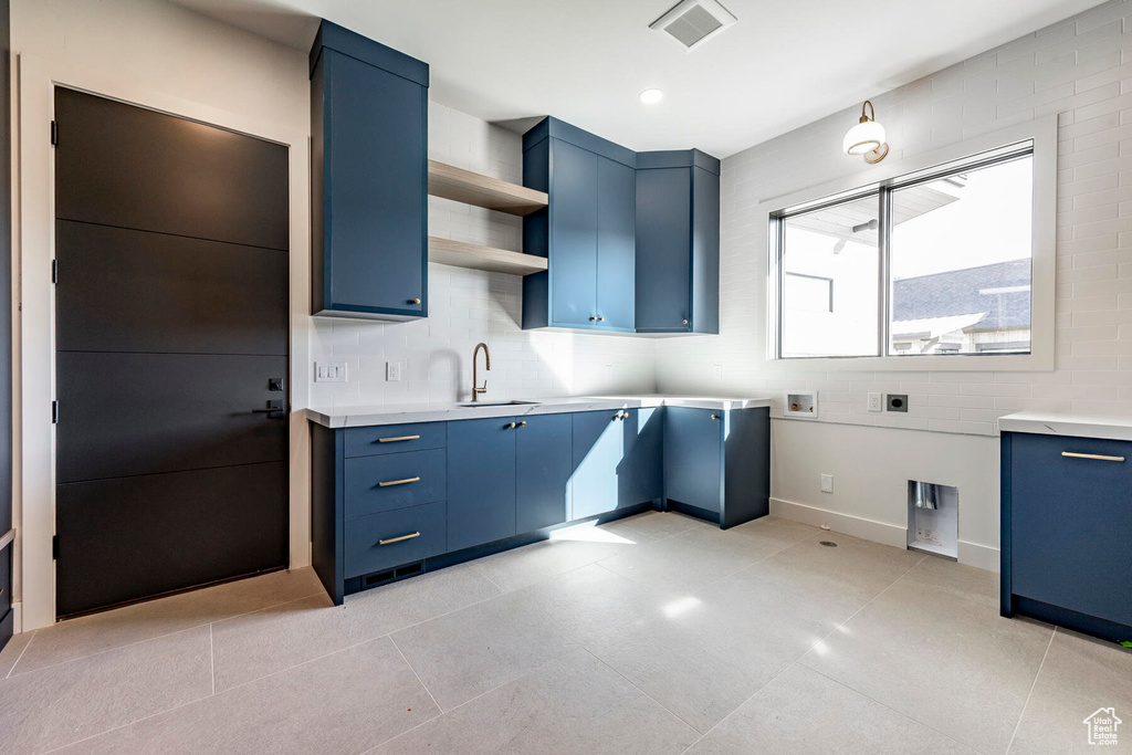 Kitchen featuring light tile patterned floors, blue cabinetry, and sink