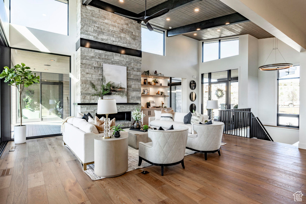 Living room with wooden ceiling, a fireplace, ceiling fan, and plenty of natural light