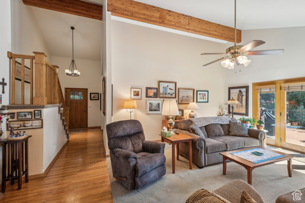 Living room featuring ceiling fan with notable chandelier, light hardwood / wood-style floors, beam ceiling, and high vaulted ceiling