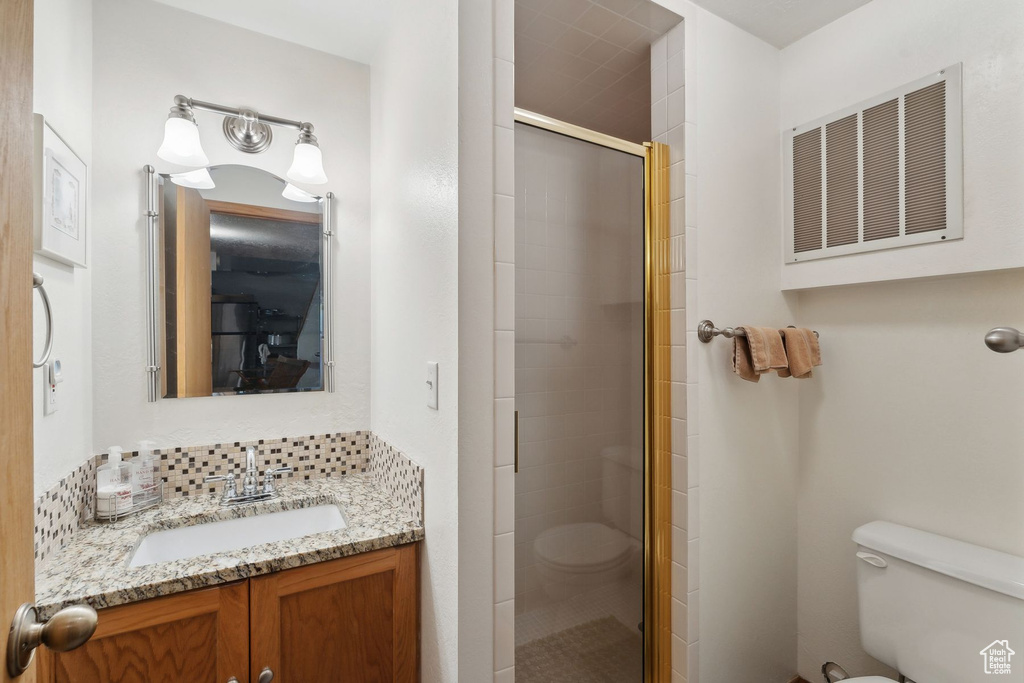 Bathroom featuring vanity, toilet, and an enclosed shower