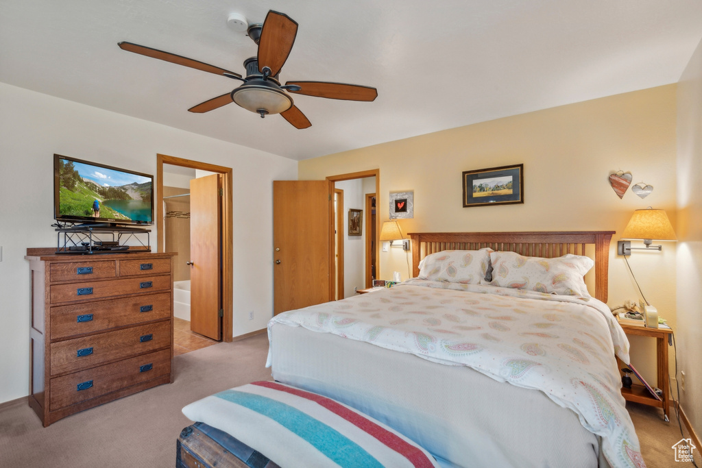 Bedroom featuring ceiling fan, light colored carpet, and ensuite bath