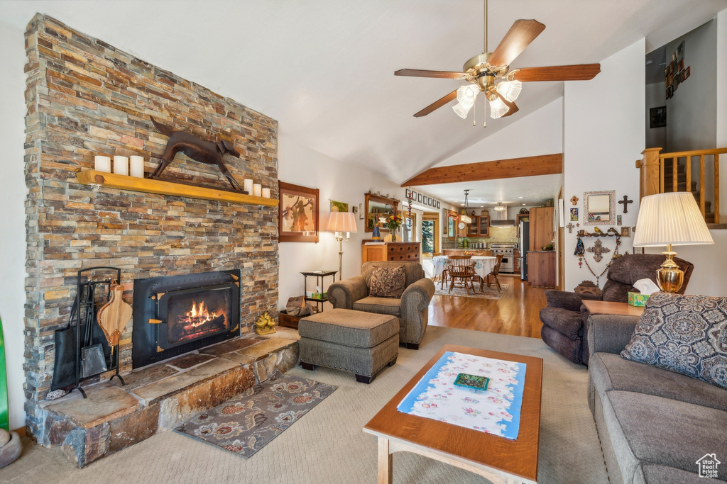 Living room featuring high vaulted ceiling, light hardwood / wood-style floors, ceiling fan, and a fireplace