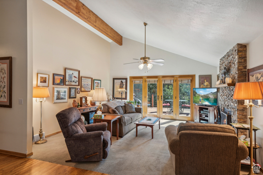 Living room featuring high vaulted ceiling, a fireplace, light wood-type flooring, beam ceiling, and ceiling fan