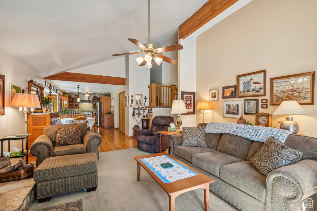 Living room featuring light wood-type flooring, beamed ceiling, ceiling fan, and high vaulted ceiling