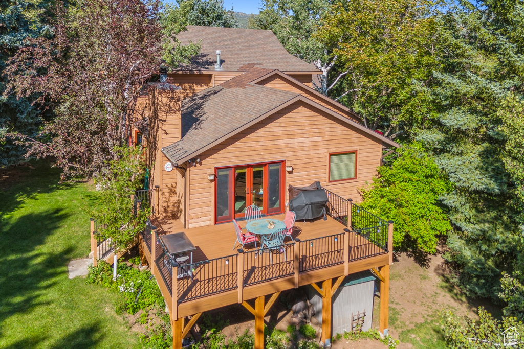 Rear view of property with french doors, a wooden deck, and a yard