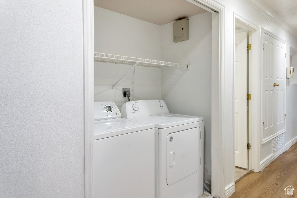 Laundry area featuring washing machine and clothes dryer and light wood-type flooring