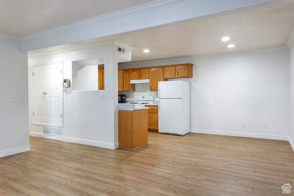 Kitchen with ornamental molding, white appliances, and light hardwood / wood-style floors