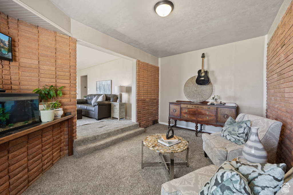 Carpeted living room with brick wall