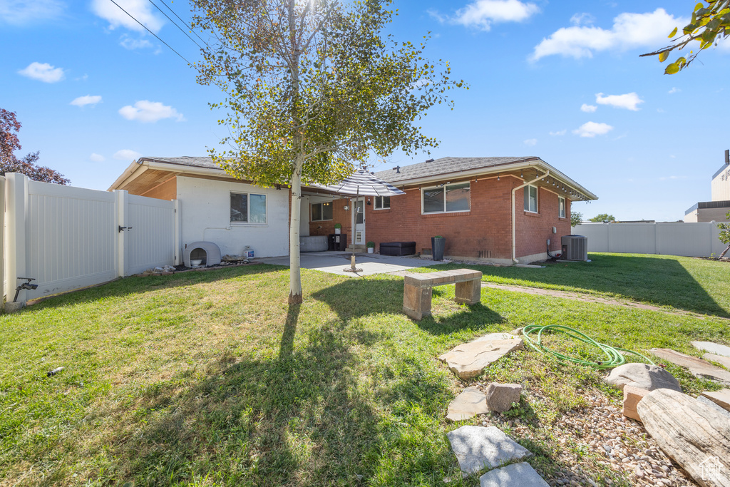 Rear view of house featuring a patio, a yard, and central AC