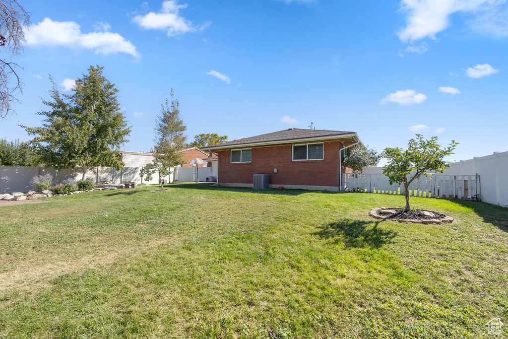 Back of property with a yard and central AC