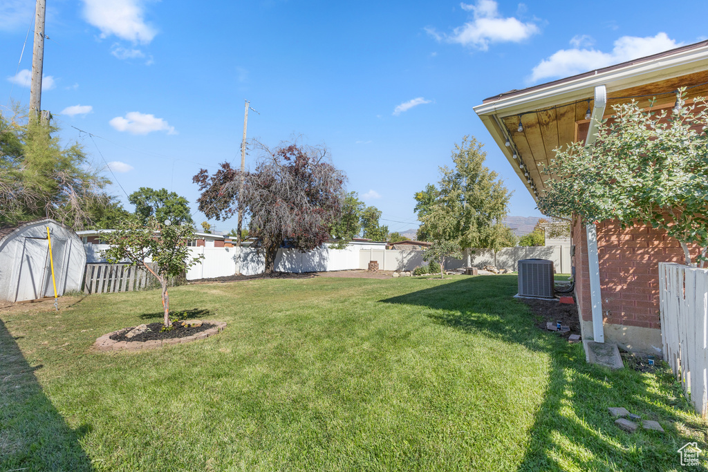 View of yard featuring a storage shed and central AC