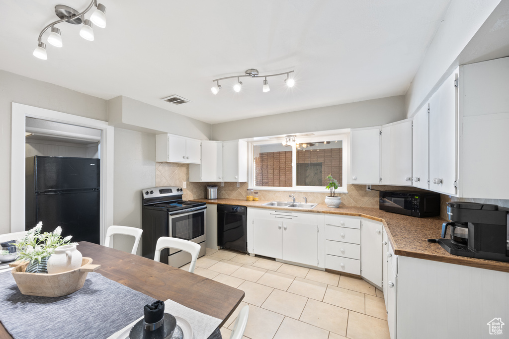 Kitchen featuring sink, white cabinetry, decorative backsplash, and black appliances