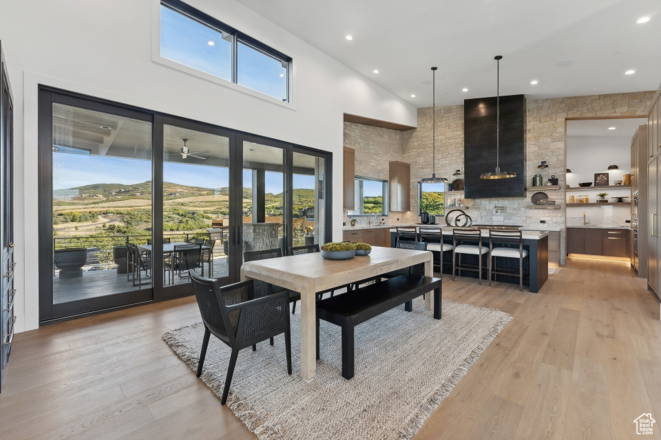 Dining area with a wealth of natural light, a towering ceiling, light hardwood / wood-style floors, and a mountain view