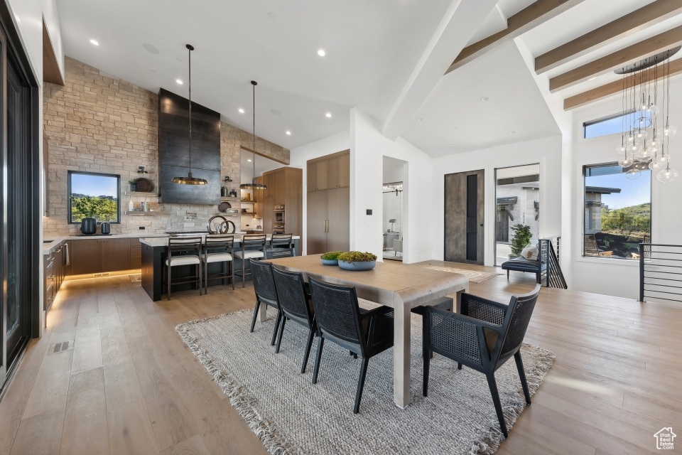 Dining room featuring an inviting chandelier, beamed ceiling, light hardwood / wood-style flooring, and high vaulted ceiling