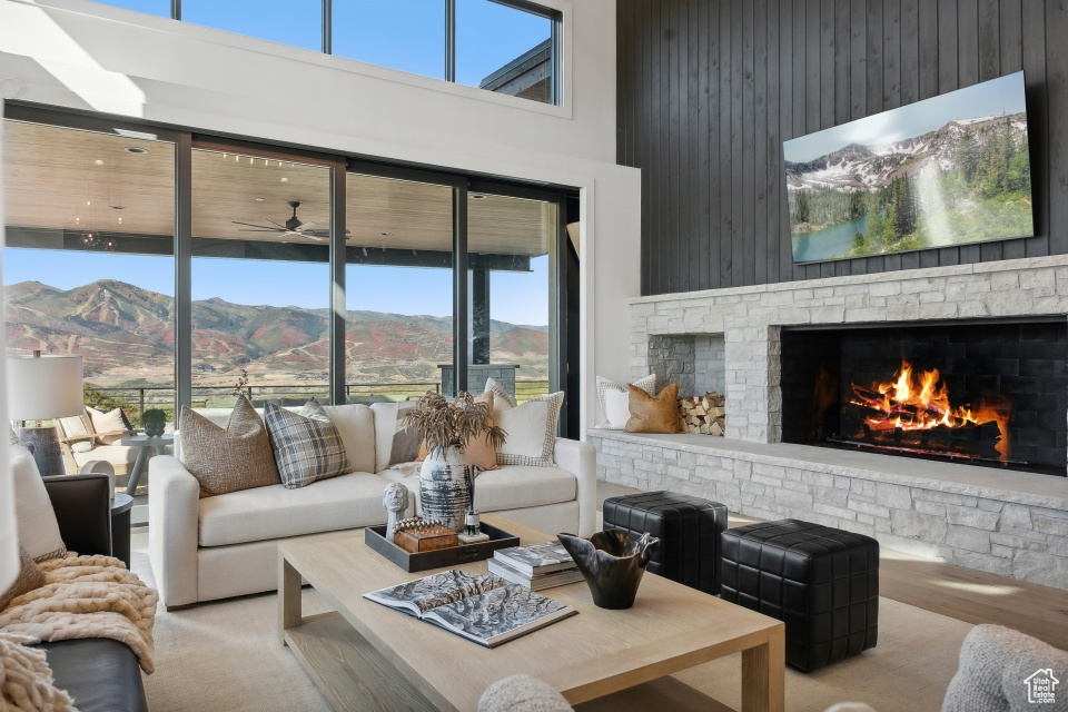 Living room with a stone fireplace, a towering ceiling, a mountain view, and plenty of natural light