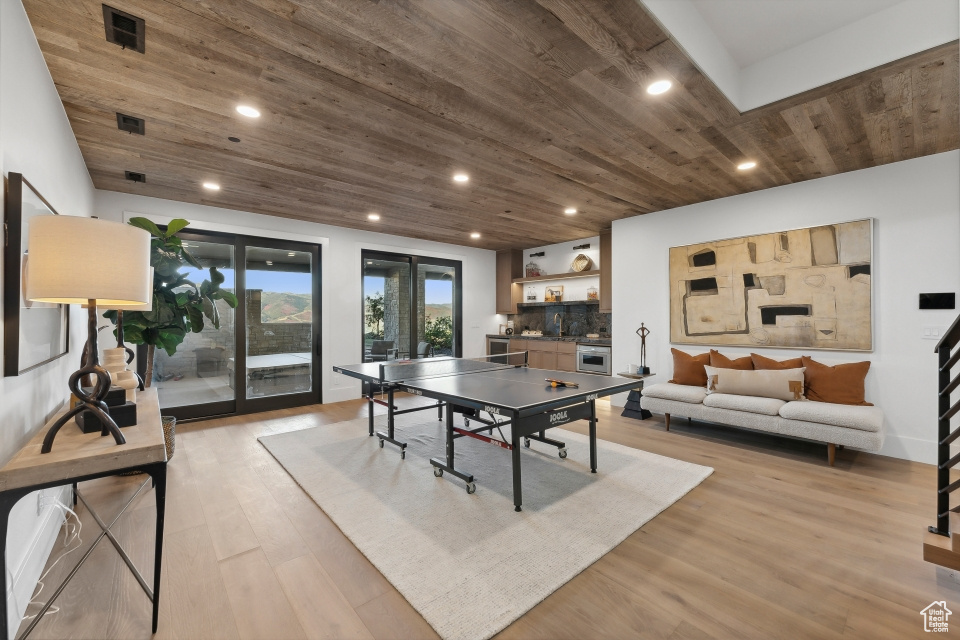 Recreation room with sink, light hardwood / wood-style floors, and wooden ceiling