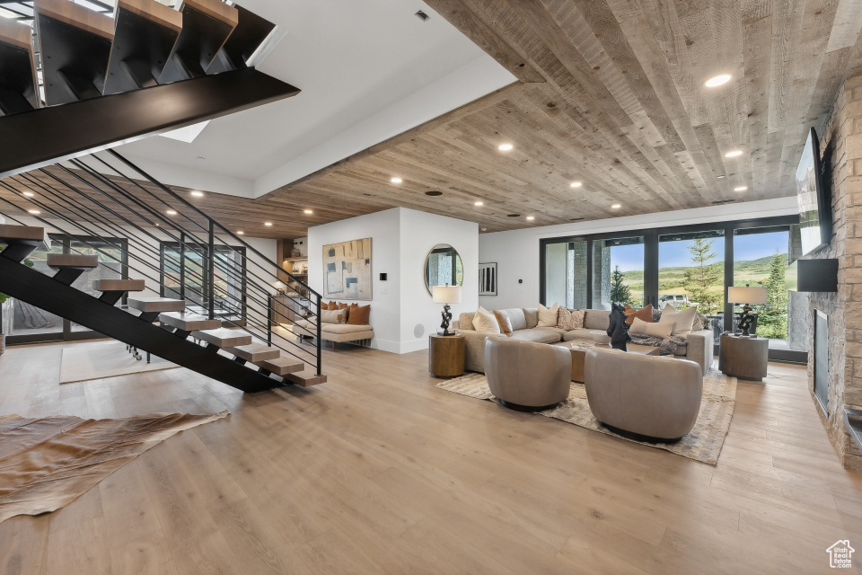 Living room with wood ceiling, light hardwood / wood-style floors, and a stone fireplace