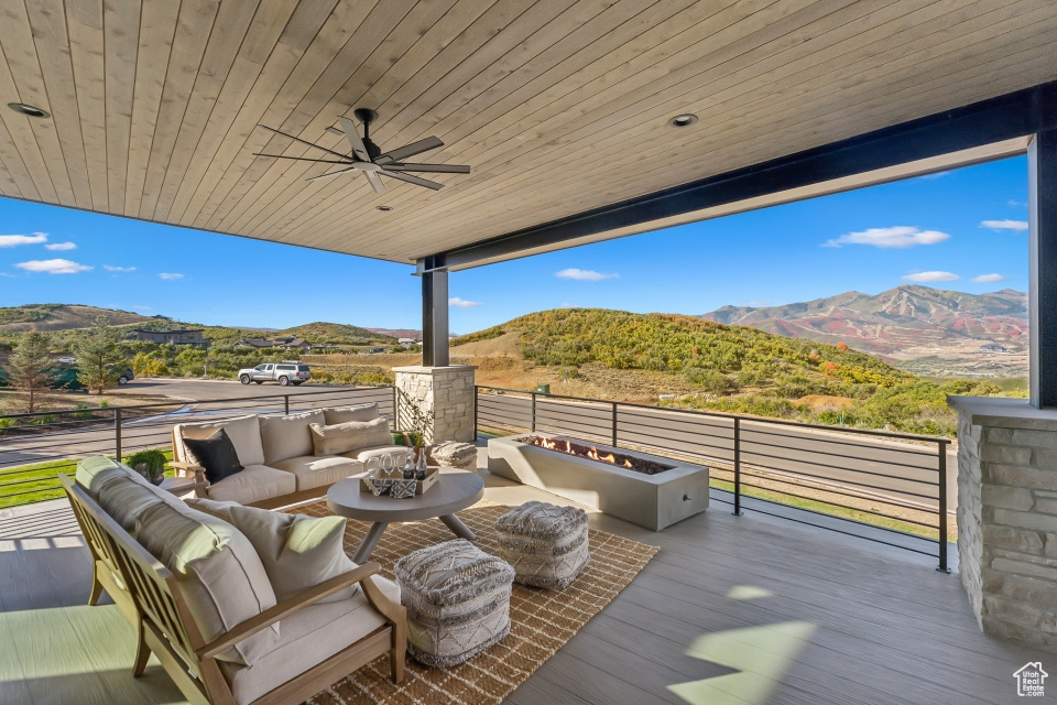 Wooden terrace featuring a mountain view, ceiling fan, and an outdoor living space