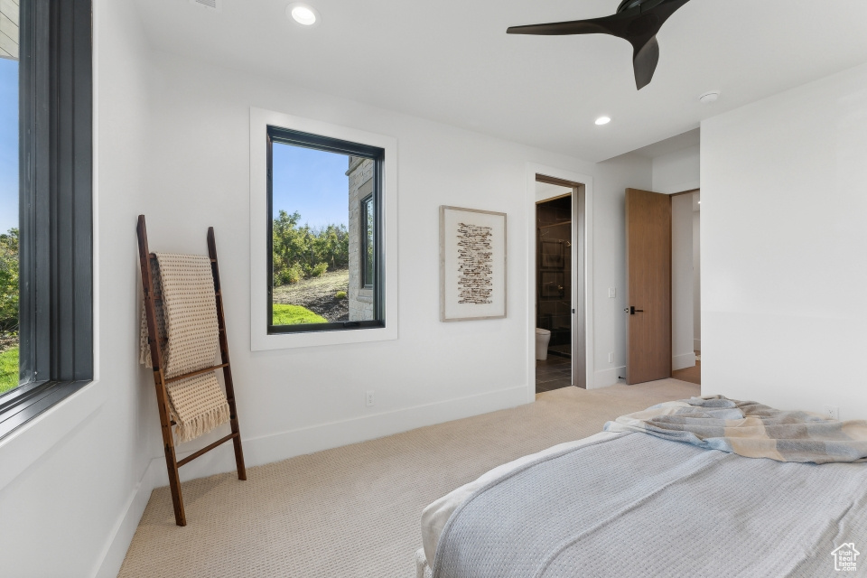 Carpeted bedroom with ensuite bath and ceiling fan