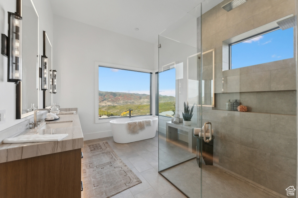 Bathroom with shower with separate bathtub, tile patterned flooring, vanity, and a mountain view