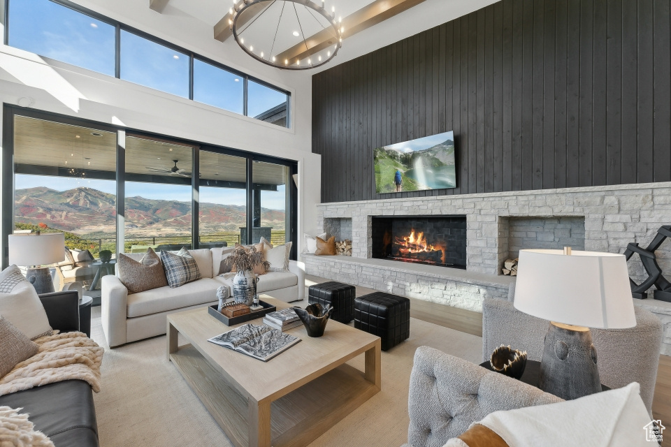 Living room featuring a stone fireplace, a healthy amount of sunlight, a high ceiling, and a mountain view