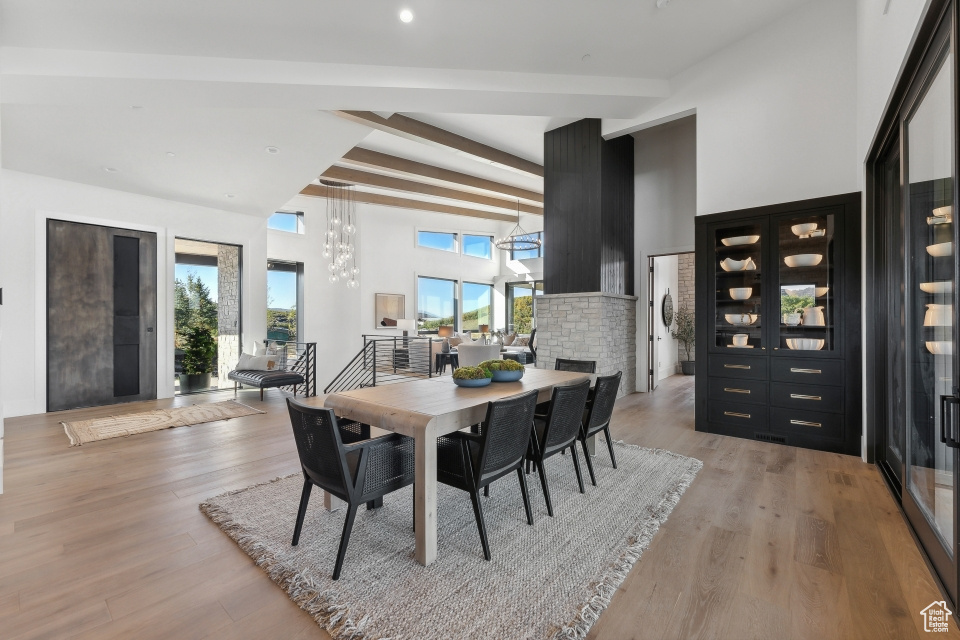 Dining area with light hardwood / wood-style floors, beam ceiling, and a towering ceiling