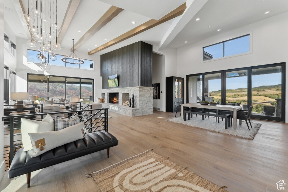 Interior space featuring beamed ceiling, a towering ceiling, light hardwood / wood-style flooring, and a brick fireplace