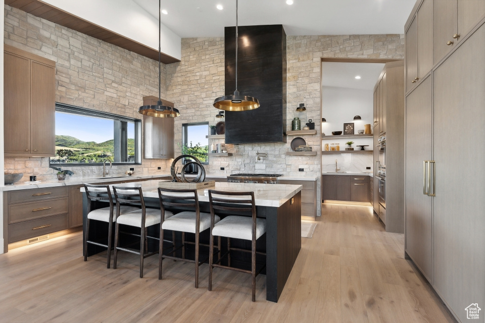 Kitchen featuring a breakfast bar, light wood-type flooring, decorative backsplash, and a center island