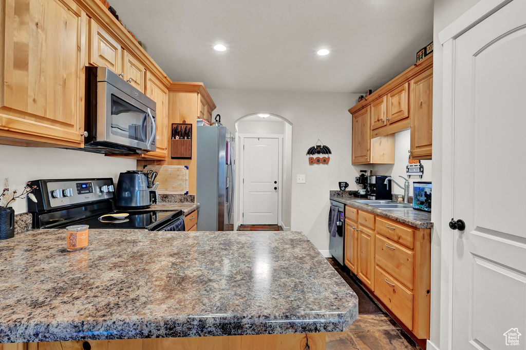 Kitchen featuring stainless steel appliances, kitchen peninsula, light brown cabinetry, and sink