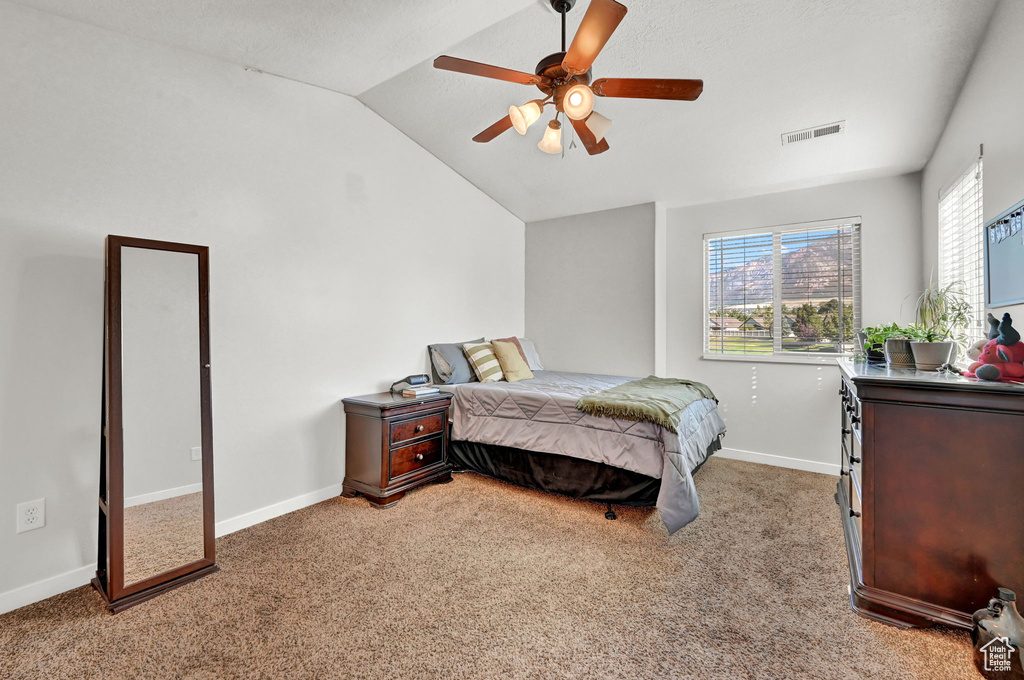 Carpeted bedroom with ceiling fan and lofted ceiling