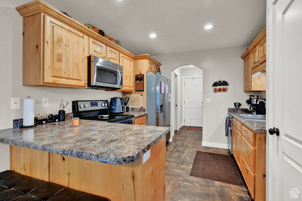 Kitchen with light brown cabinets, stainless steel appliances, sink, and kitchen peninsula