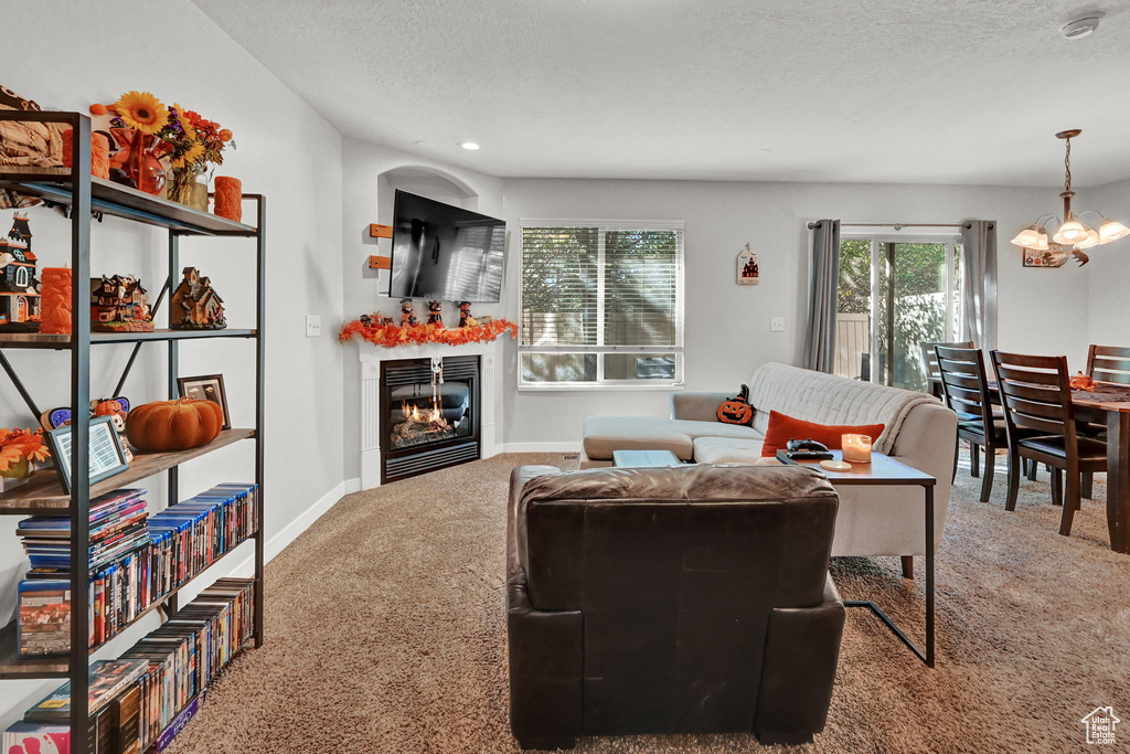 Carpeted living room with an inviting chandelier and a textured ceiling