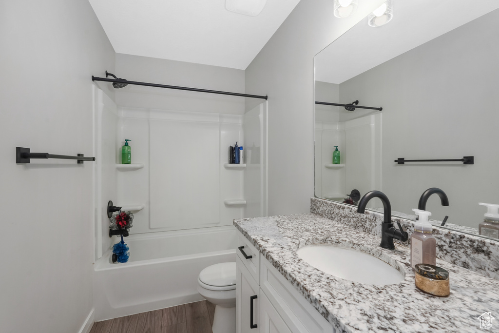 Full bathroom with shower / bathing tub combination, vanity, hardwood / wood-style floors, and toilet