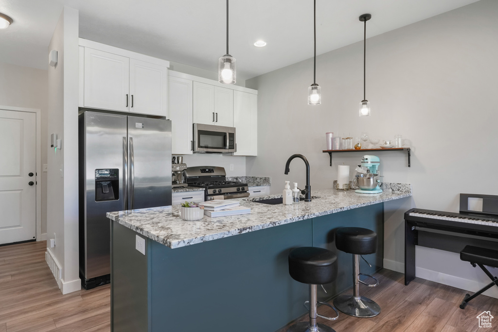 Kitchen featuring light stone counters, stainless steel appliances, sink, and white cabinetry