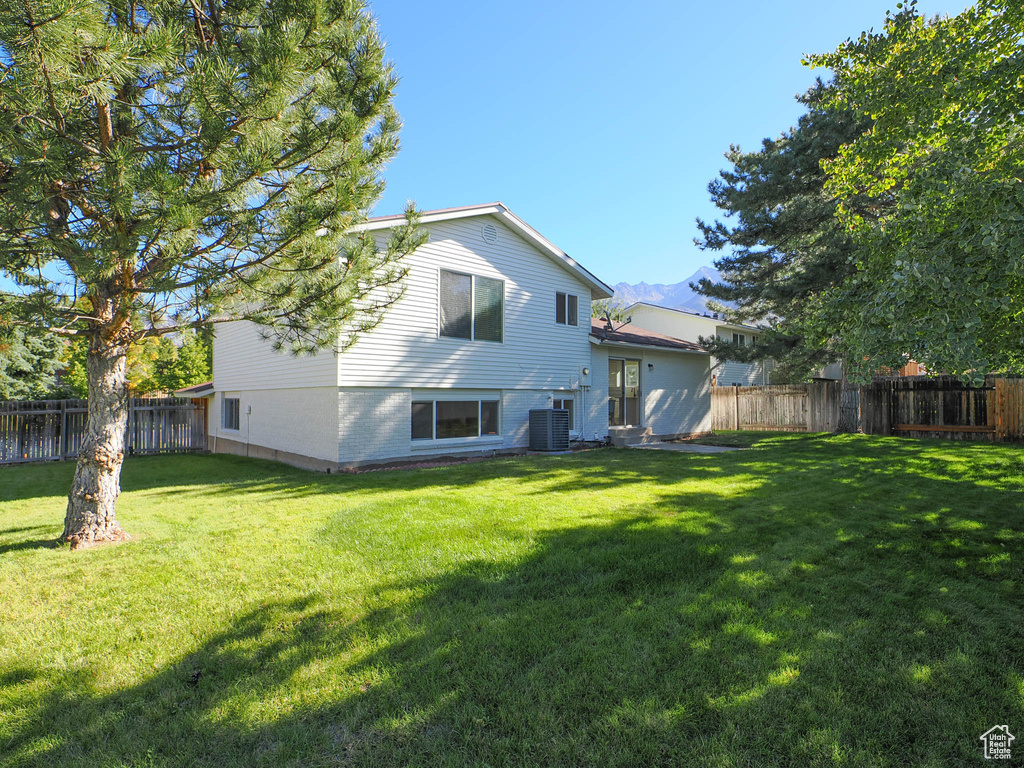 Back of property with a lawn and central air condition unit