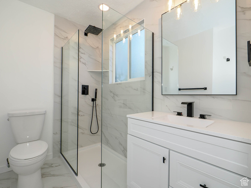 Bathroom with decorative backsplash, vanity, a textured ceiling, toilet, and an enclosed shower