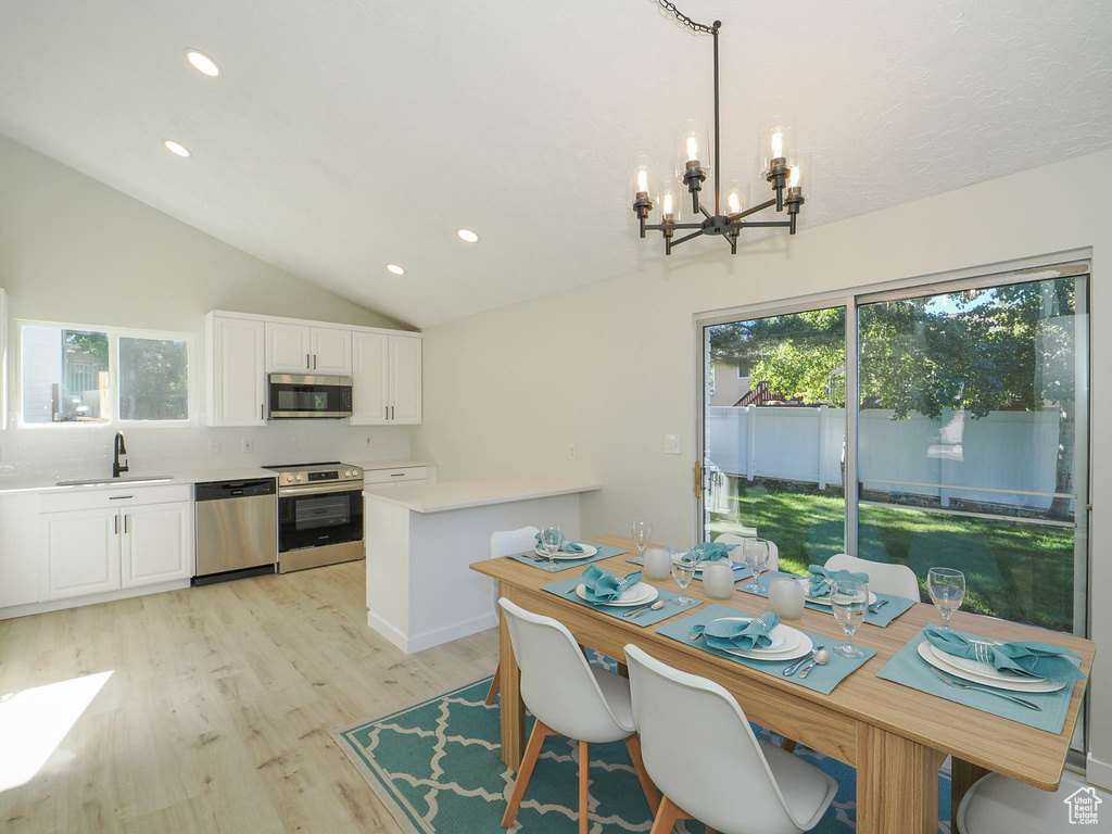 Dining space featuring light hardwood / wood-style flooring, lofted ceiling, a chandelier, and sink