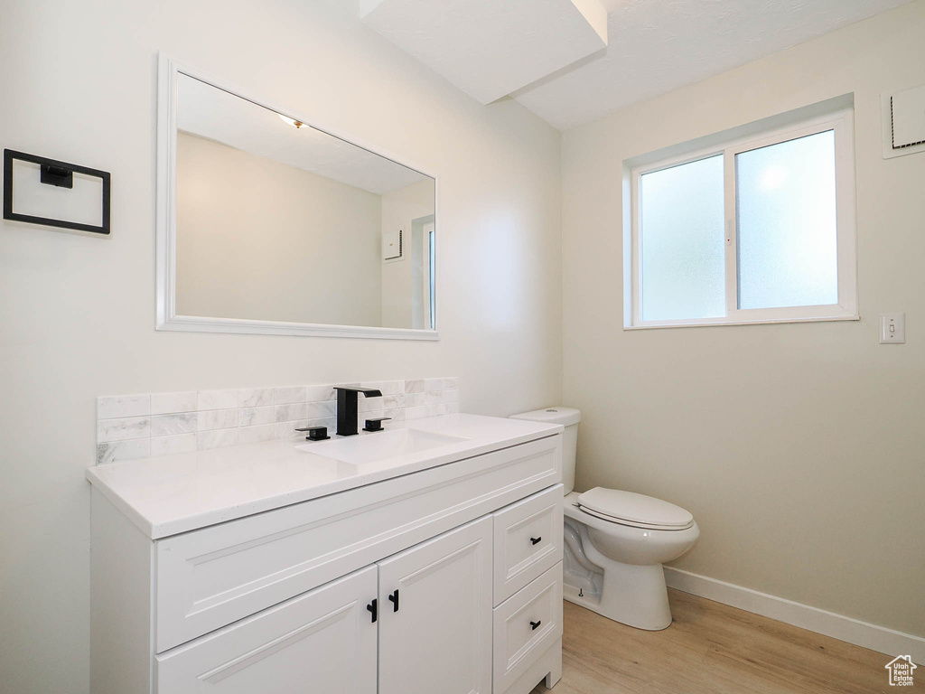 Bathroom with hardwood / wood-style floors, tasteful backsplash, vanity, and toilet